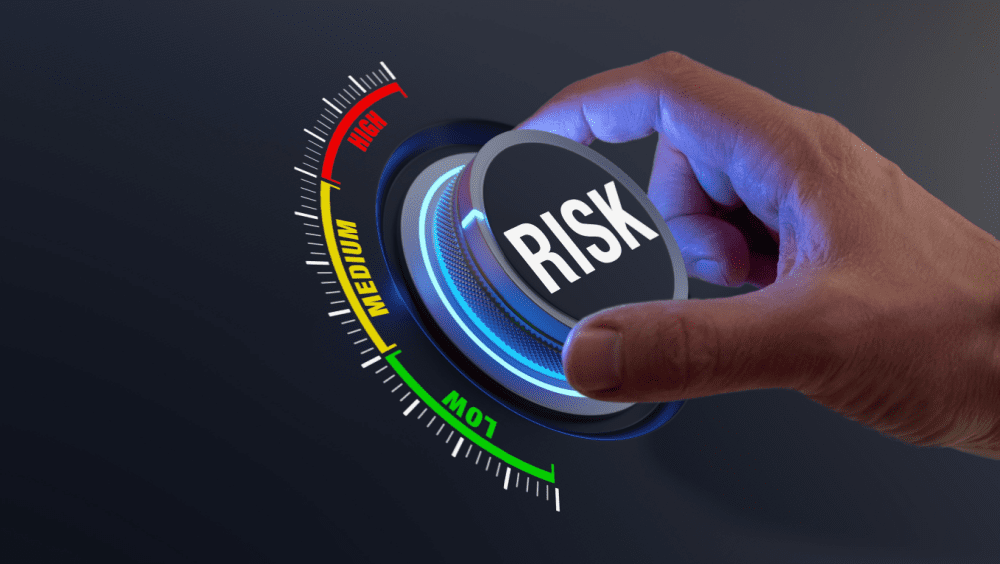 Graphic of a hand turning a dial labelled 'Risk' between 'Low', 'Medium' and High'