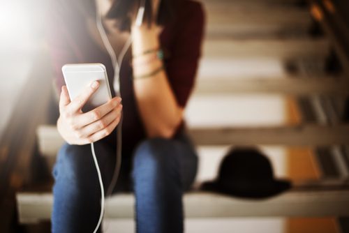 Young lady listening via earphones to her device.